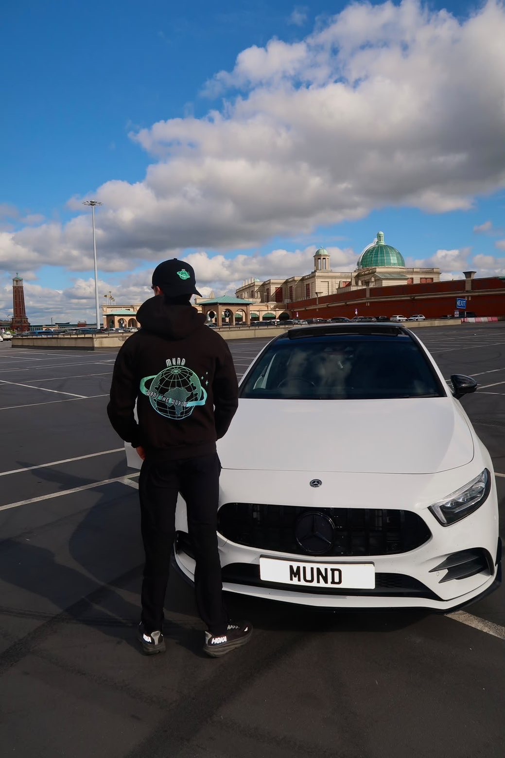 MUND cap and hoodie styled beside a white car